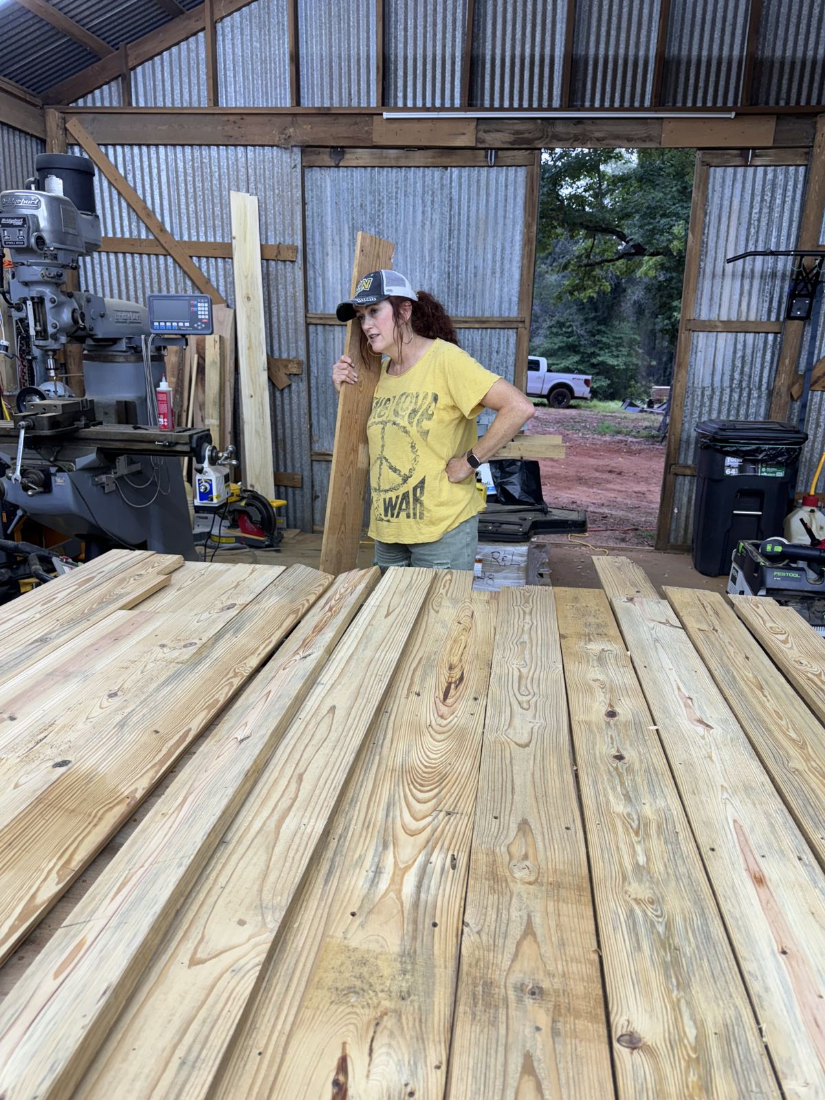 Carrying a board through the shop past rough-sawn pine boards